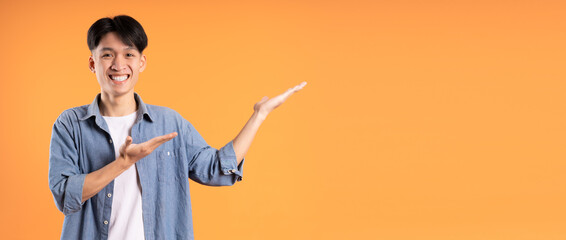 image of young asian man posing on orange background