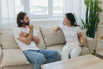 Obraz premium Male and female Asian friends sitting on the couch and having fun talking to each other with a smile having a good time together. Lifestyle in happiness at home