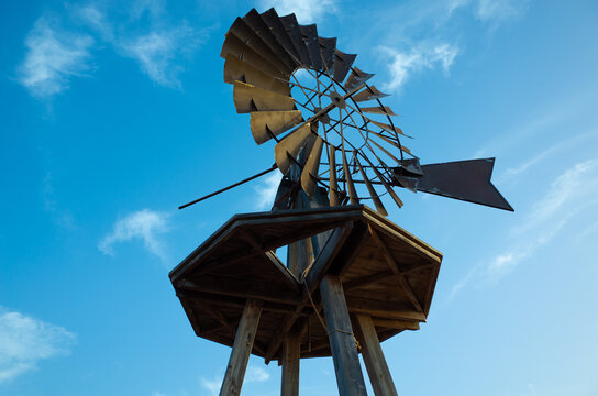 View of local windmill at beach Playa del Jablillo, Costa Teguise. Old architecture, with wood and rusty metal. Background colorful blue sky with beautiful clouds. Lanzarote, Canary Islands, Spain.