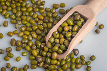 Raw green peas in wooden spoon on white background