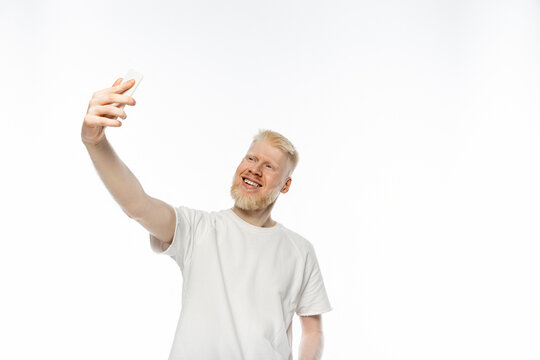 happy albino man in t-shirt taking selfie on smartphone on white background