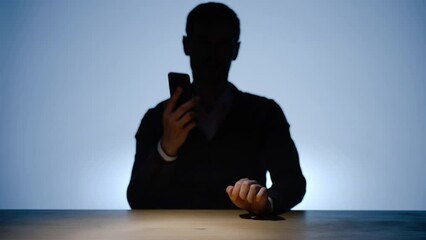 Soft light falls on hands of unrecognizable male silhouette, using mobile phone, dialing, calling