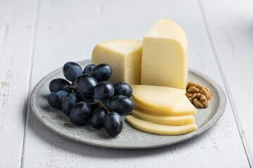 Sliced cheese Caciotta, served with grapes and walnuts, selective focus