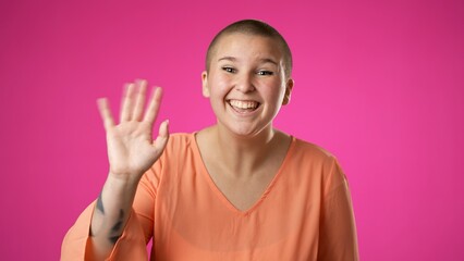 Happy gender fluid non binary young woman 20s video chatting, as seen from the pov point of view of the computer screen camera isolated on pink background.