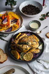 Dinner with oven baked spring chicken (coquelet jaune) in French herbs and citruses, baked vegetables and lentils on white background.