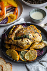 Dinner with oven baked spring chicken (coquelet jaune) in French herbs and citruses, baked vegetables and lentils on white background.
