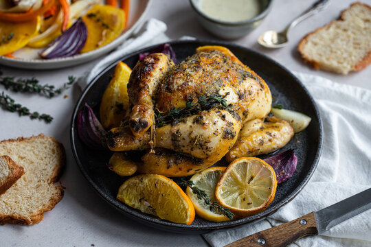 Dinner with oven baked spring chicken (coquelet jaune) in French herbs and citruses, baked vegetables and lentils on white background.