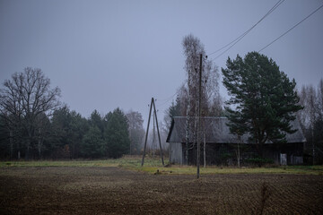 Fototapeta na wymiar old wooden barn in Latvia countryside, dark gloomy sky, electric power line