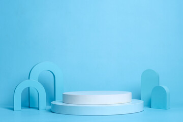 Round white platform podium and various blue geometry on pastel blue background.  Minimal creative composition for cosmetics or products presentation.
