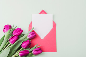 Purple tulips, red envelope with blank sheet on neutral background. Valentine's Day, Mother's Day holiday concept. Top view, flat lay, mockup