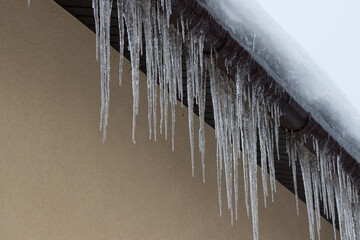 Big icicles on the roof of a townhouse.  Roof of home covered with icicles in winter. Dangerous problem