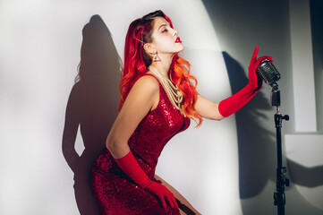 Gorgeous red haired woman with retro microphone singing on stage