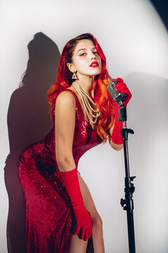 Gorgeous red haired woman with retro microphone singing on stage