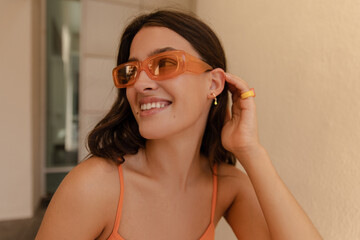 Close-up smiling young caucasian female looking at distance collects her hair spends leisure time....