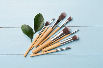 Natural biodegradable makeup brushes on wooden background, top view