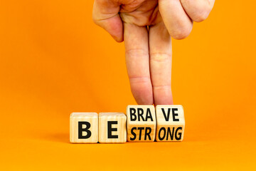 Be strong and brave symbol. Concept word Be strong Be brave on wooden cubes. Beautiful orange table orange background. Businessman hand. Business be strong and brave concept. Copy space.