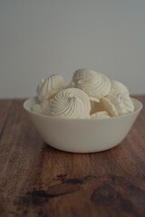 meringue in a white plate on a whitebackground and wooden surface