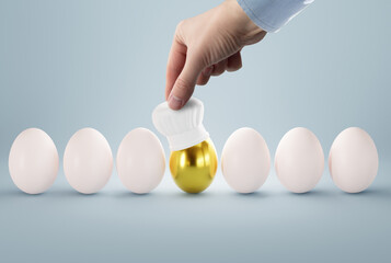 The hand puts a cook hat on the egg. The concept of cooking, making food, checking the recipe. Scrambled eggs and cooking eggs.