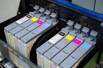 Row of inkjet printer CMYK cartridges - cyan, magenta, yellow, key or black colors - close up view.
