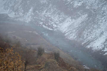 View of the river Chandra flowing between the snow covered mountains of the Tinnan valley during the winter season at Himachal Pradesh, India. River flowing in between the snow covered mountains.	