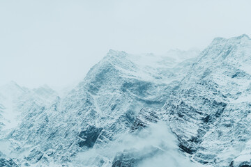 Obraz premium Closeup shot of snow covered Himalayan mountain after the blizzard at Lahaul Spiti in Himachal Pradesh, India. Mountains covered by snow during the winter season. Natural winter background.