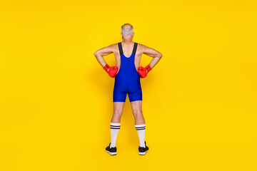 Fototapeta na wymiar Full length photo old age pensioner wear blue costume showing behind arms waist good figure muscles red boxing gloves isolated on yellow color background