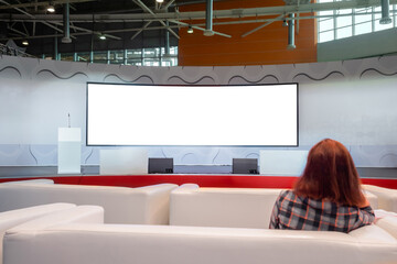 Redhead woman looking at wide large wall blank interactive white display of modern technology...
