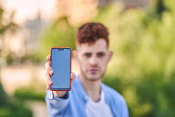 Red-haired hispanic young man showing a screen smartphone in the city. high quality photo 