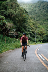 Naklejka premium A young female cyclist riding her gravel bike in the mountains.
