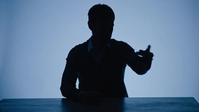 Hidden man in shade, points finger at people, calling for report, makes a hand cutting throat sign