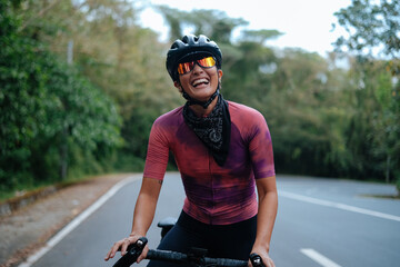 A young woman cyclist happily laughing. - obrazy, fototapety, plakaty