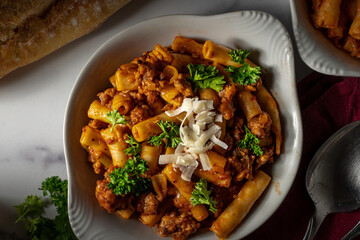 Baked ziti pasta with Italian sausage and marinara sauce. Garnished with parsley and shaved parmesan cheese.