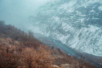 View of the river Chandra flowing between the snow covered mountains of the Tinnan valley during the snowfall in winter at Himachal Pradesh, India. River flowing in between the snow covered mountains.