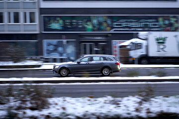 Panning of gray car in the city. Limousine driving fast in road traffic. Road in winter at rush hour. Stuttgart, Germany.