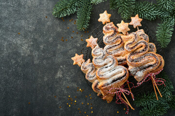 Christmas tree shape puff pastry cakes with chocolate filling, sugar powder and lollipops on old dark background. Christmas, New Year Appetizer. Festive idea for Christmas or New Year dinner.