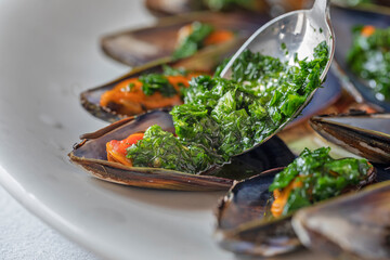 Close up of parsley pouring on some mussels.