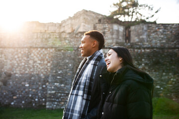 Man and woman walking in front of an old stone wall. Multiracial couple in love. Kale Fortress in Skopje, North Macedonia