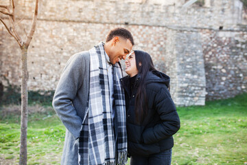 Man and woman posing in front of an old stone wall. Multiracial couple in love.