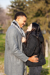 Man and woman posing in the park. Multiracial couple in love.