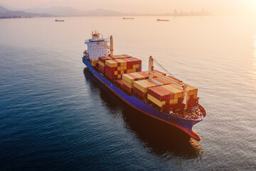 Cargo ship with containers in the open sea at the sunset, aerial drone view