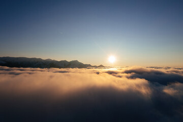 Caucasian mountains above the clouds at the sunset. Cloudscape, aerial view