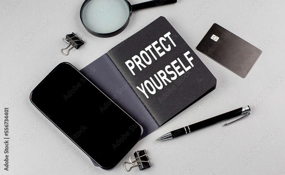 Poster protect yourself text written on black notebook with smartphone, magnifier and credit card