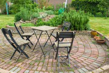herb spiral in the garden and table with chairs