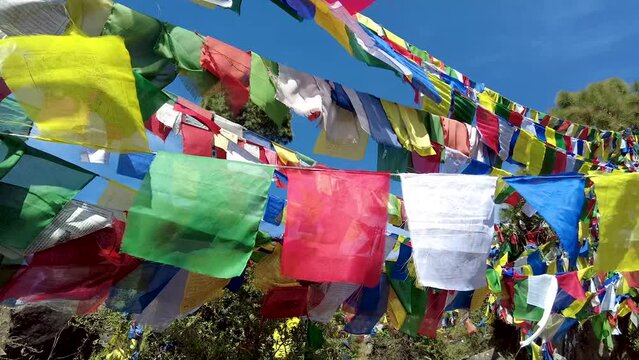 A lot of Tibetan flags with mantras at Rewalsar, India. Colorful flags hanging. Background blue sky