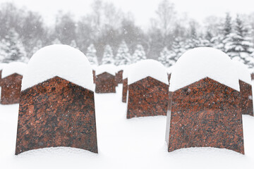tombstone in a cemetery covered with snow in winter