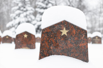 tombstone in a military cemetery covered with snow