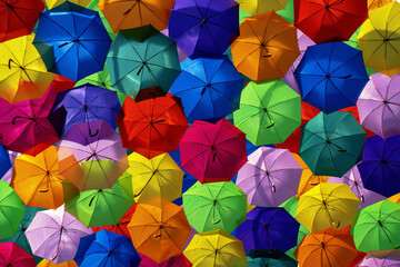 Fototapeta na wymiar Colorful umbrellas in the sky. City street decorated with colorful umbrellas. Umbrella Sky Project in city of Agueda, Portugal. Multicolored background with many umbrellas