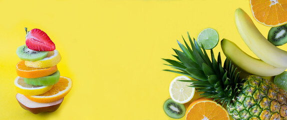 Pyramid of chopped fruit in balance and tropical fruits on the yellow background. Copy space. Close-up.