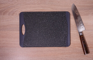 Empty plastic black board and kitchen knife on the table