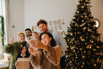 Cheerful family taking selfie while standing together near Christmas tree
